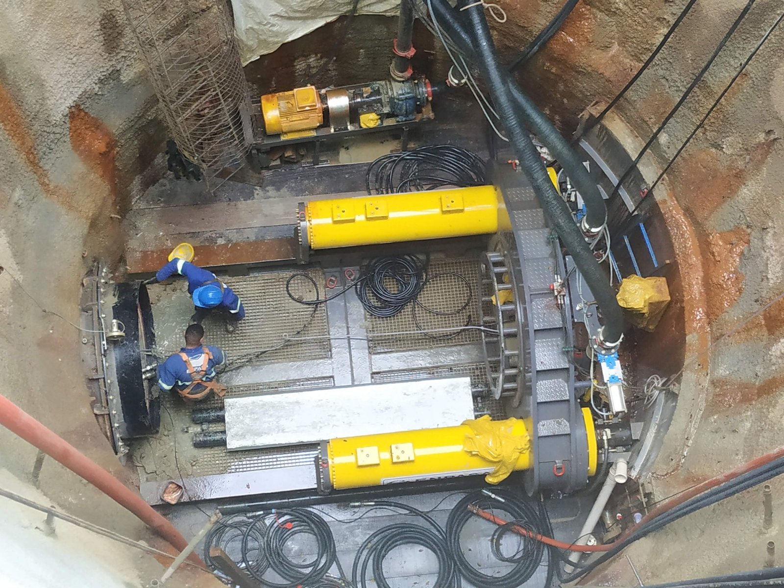 Equipe operando shield em poço de ataque com cilindros hidráulicos amarelos
